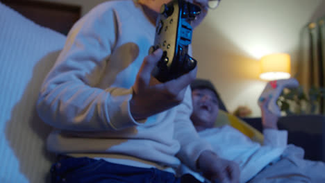 Close-Up-On-Hands-Of-Two-Young-Boys-At-Home-Playing-With-Computer-Games-Console-On-TV-Holding-Controllers-Late-At-Night-9